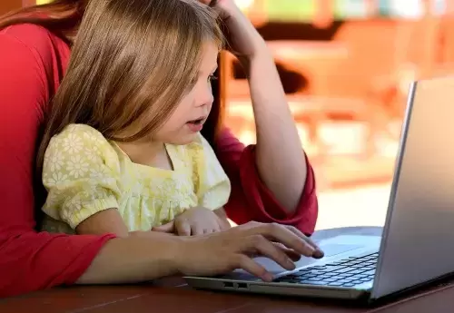 Young girl sitting in parents lap while they are on a laptop.
