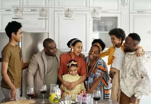 Black family stands around in kitchen smiling